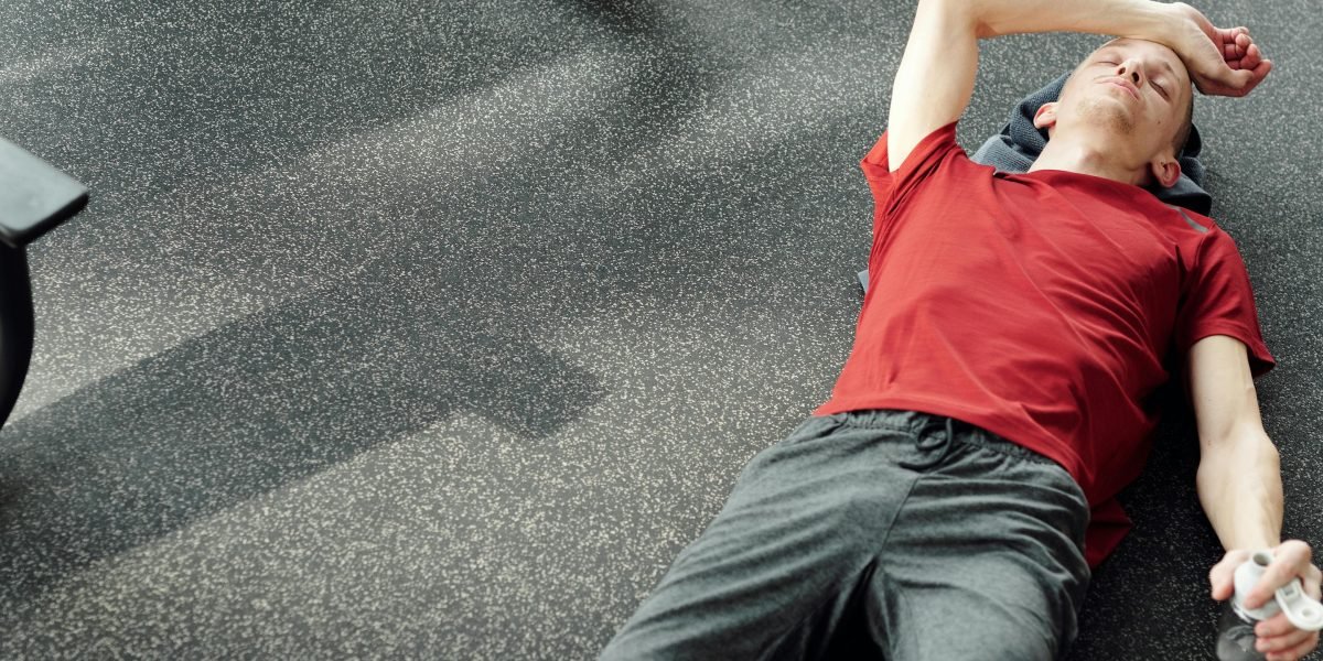 An athlete stretching or resting after an intense workout, symbolizing the crucial phase of muscle repair and growth.